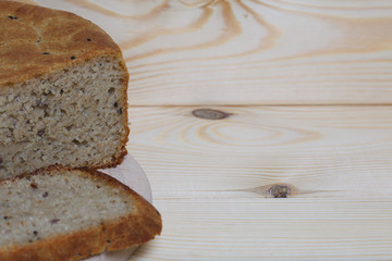 Freshly baked bread. A loaf of bread is cut and lies on a cutting board. Background from pine...