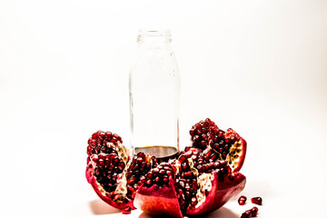 Pomegranate isolated at the white background with glass clear bottle