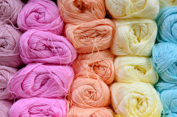 background of rows skeins of thin fluffy wool yarn for knitting different pastel colors