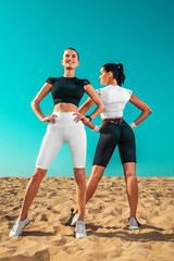 Two young sportsmens women, fit athletes are standing on the sky background before run. Healthy lifestyle and sport. Friends in black and white sportswear. Fitness concept.