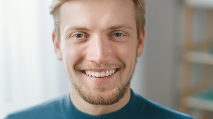Portrait of Handsome Blonde Young Man Smiling, while Looking at Camera. Happy Attractive Guy with Blue Eyes