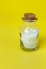 Classical Homeopathy globules  and vintage glass bottles on  yellow background. Alternative Homeopathy medicine herbs, healtcare and pills concept.   Place for text.
