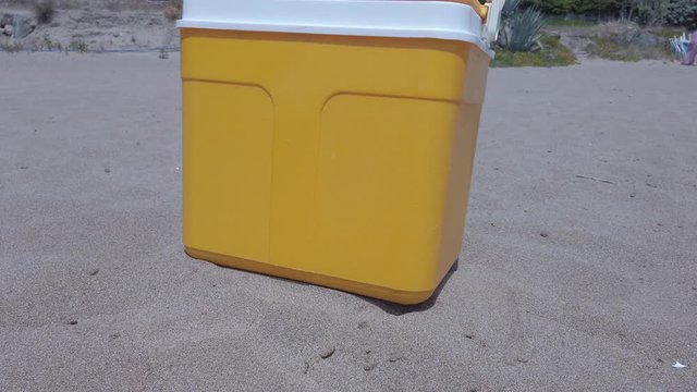 Yellow portable handheld mini fridge on beach