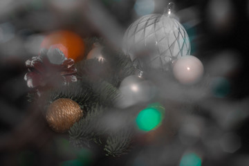 Art installation on a black background for New Year or Christmas from spruce twigs, glass balls, cord-balls, pine cone and mandarin through the prism of light.
