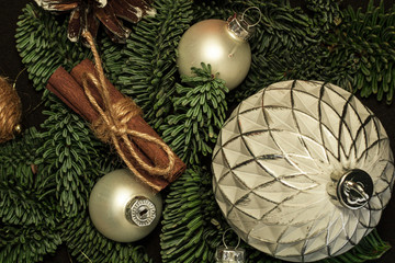 Close-up art installation for New Year or Christmas from spruce twigs, glass balls, cord balls, pine cone and cinnamon sticks.