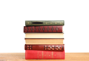 Stack of old vintage books on wooden table against white background