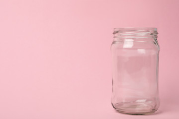 Open empty glass jar on pink background, space for text
