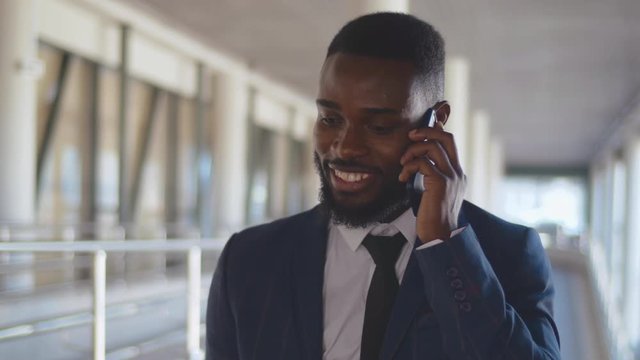Modern african businessman talking on a mobile phone in office hall or airport