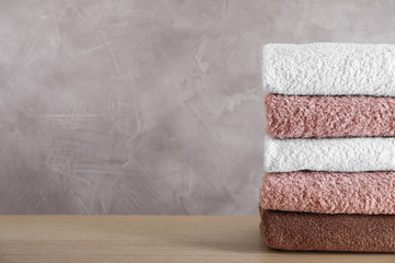 Stack of clean bath towels on wooden table. Space for text