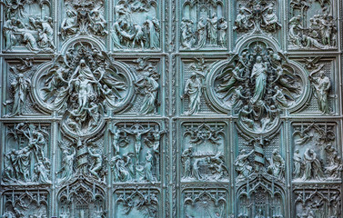 Beautiful bas-reliefs on the bronze door of  building of the Milan Cathedral (Duomo di Milano), the cathedral church of Milan, Lombardy, Italy. Dedicated to the Nativity of St Mary.