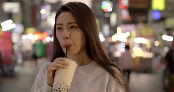 young woman enjoy bubble milk tea with street food in  Night Market