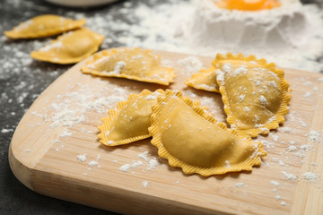Raw ravioli on wooden board, closeup view. Italian pasta