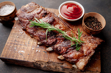 grilled pork ribs on a cutting board with spices on a stone background 