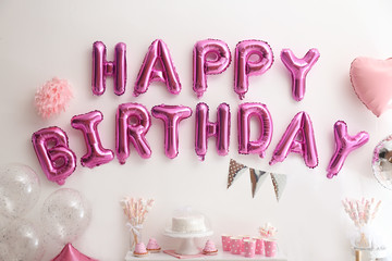 Phrase HAPPY BIRTHDAY made of pink balloon letters on white wall