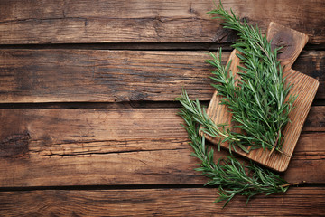 Fresh rosemary on wooden table, flat lay. Space for text