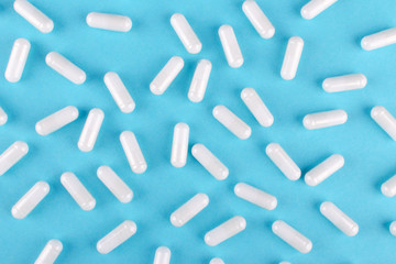 white medicine capsules on blue background, view from above