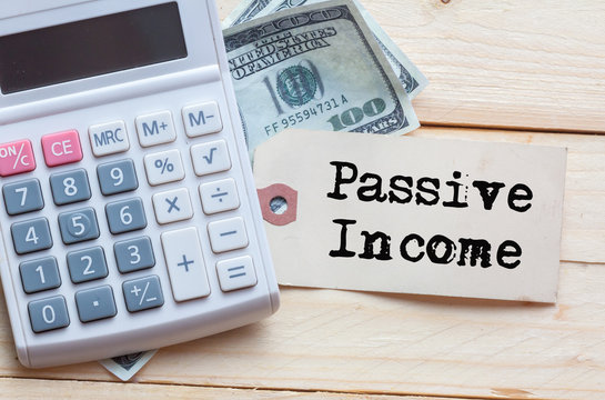 Passive Income Words on tag with dollar note and calculator on wood backgroud,Finance Concept
