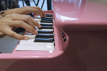 Close up the hands of a young woman playing pink tiny piano, with Selective focus