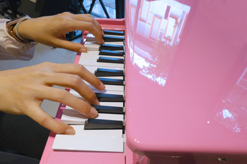 Close up the hands of a young woman playing pink tiny piano, with Selective focus