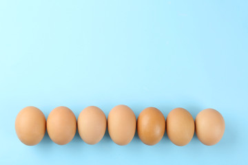 Raw chicken eggs on light blue background, flat lay. Space for text
