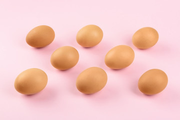 Raw chicken eggs on pink background, above view