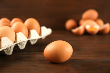 Raw chicken egg near carton tray on wooden table