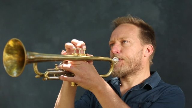 Hombre de mediana edad de pelo rubio tocando la trompeta