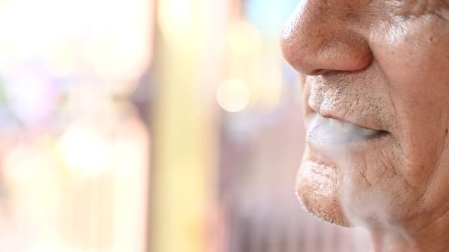 4K Close up old asian handsom man smoking cigarette outdoors. Old man smoking concept background. Man addiction tobacco, smoker poison, man's lips, smoke fire light.