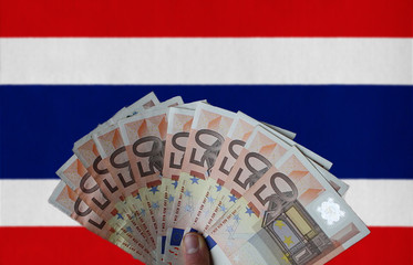 Thailand flag with Euro banknotes in the hand
