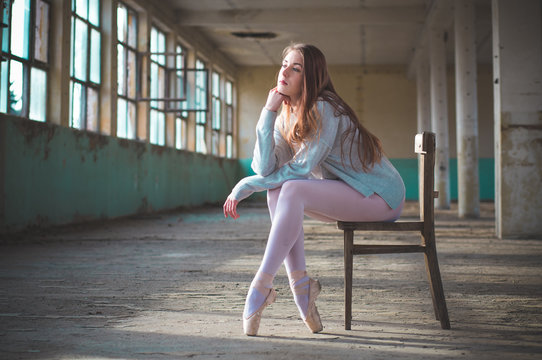 Photo of ballerina while shes sitting on the chair in an old building.