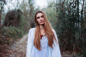 Outdoor portrait of beautiful girl in white nightgown, looking like a fairy.