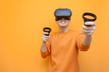 guy in VR glasses on an orange background, a gamer plays a virtual game and screams