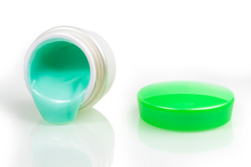 jar with cream and a green lid. the bank is open and there is a cruise nearby. close-up. on white background.