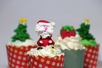 Christmas cupcakes decorated with Santa Claus and out focus Christmas cupcakes.