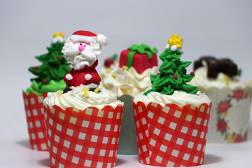 Christmas cupcakes decorated with Santa Claus and out focus Christmas cupcakes.