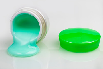 jar with cream and a green lid. the bank is open and there is a cruise nearby. close-up. on white background.