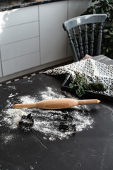 A wooden rolling pin lies on a table among flour