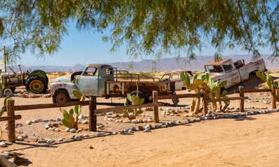 Autowracks stehen wie in einer Oldtimer Ausstellung an der Tankstelle / Rastplatz Solitaire am Rande der Wüste Namib, Region Khomas, Namibia