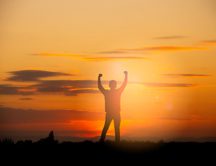 Silhouette of a happy man raised hands up as a successful, victory and achieve a business goal in the sunset sky background.