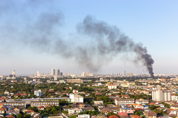 Some building or house is on fire with huge smoke on the air in the evening. 