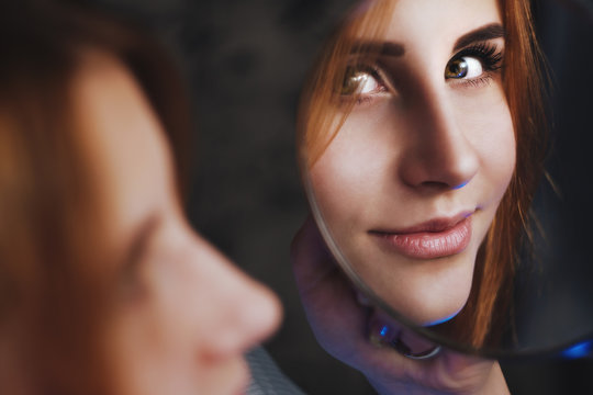 Face of a cute gingerhead reflecting in a small round hendheld mirror