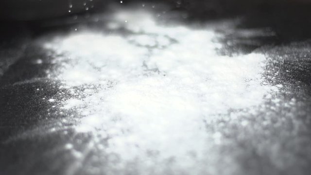 Slow motion of cook sprinkling flour on table