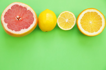 color citrus fruits on green background. Tropical fruit. Citrus background. Flat lay. Top view. With copy space for text.