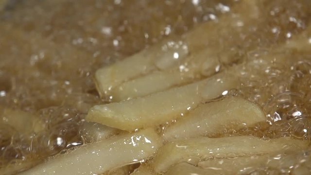 Pieces of potatoes floating in hot oil