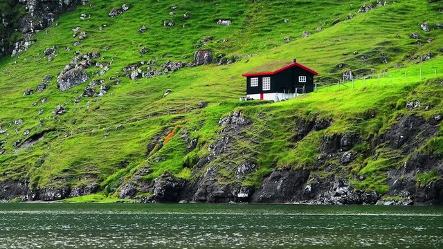 Traditional turf-top faroese house on Pollurin Laguna, Saksun village, Atlantic ocean coast, Streymoy island, Faroe Islands, Denmark. UHD 4k video