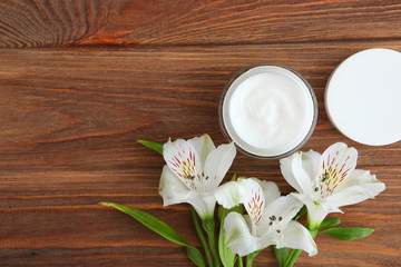 Care cream and flowers on a colored background top view. Skin care cosmetics.