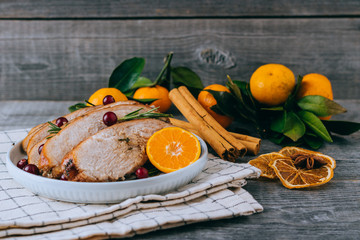 Roasted turkey or chicken with orange slices in plate for Christmas dinner served and festive decoration on dark rustic background