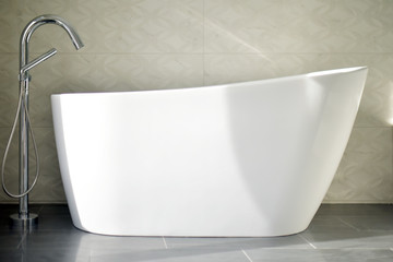 Elevated modern white bathtub with exposed faucet  