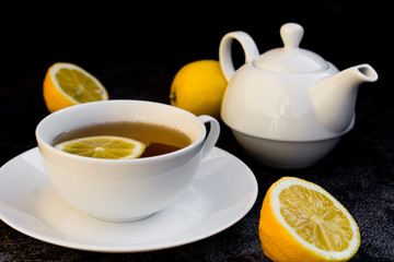 Teapot and cup of tea with fresh lemon.