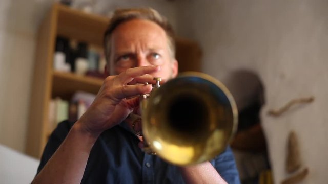 Hombre de mediana edad de pelo rubio tocando la trompeta